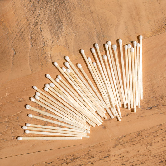 A pack of white matches laid out on a wooden surface.