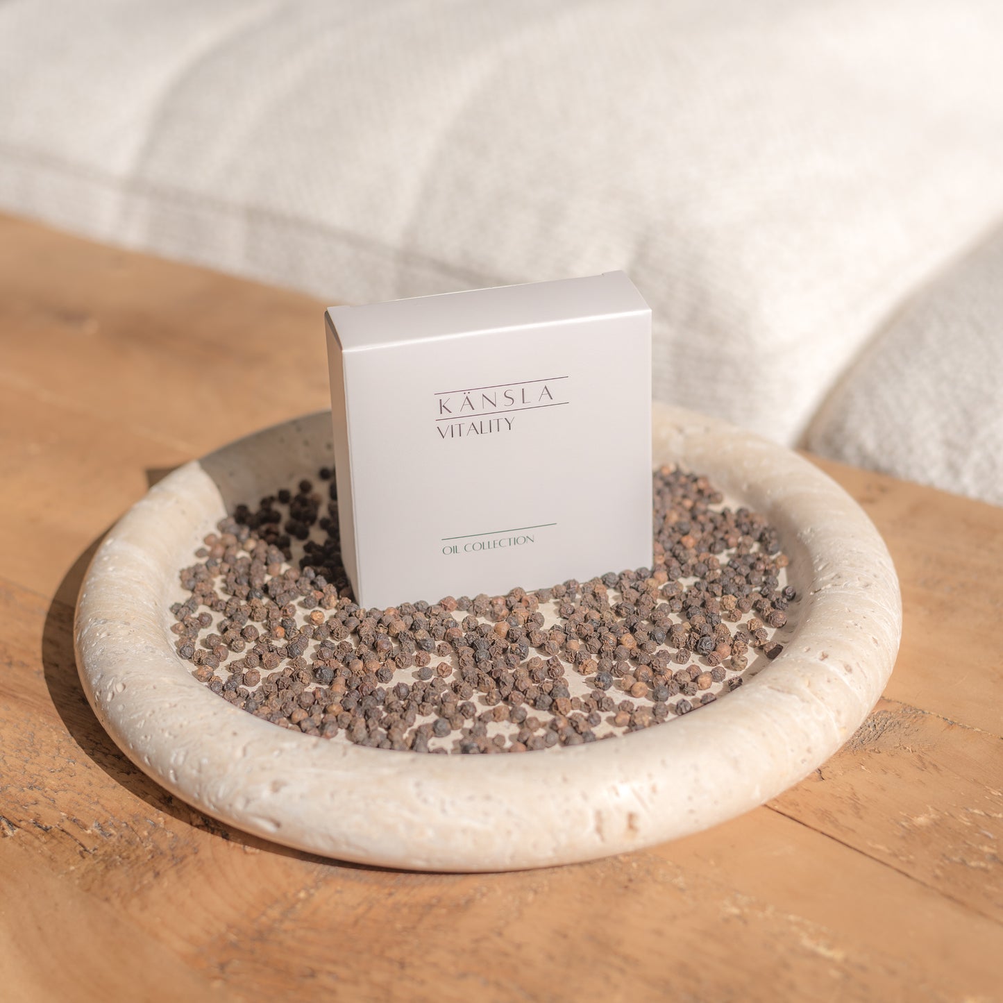 the oil collection box placed on a travertine display tray with dried peppercorns around the outside