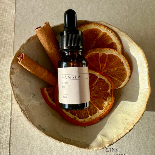 A lifestyle image of the kansla festive oil sat in a bowl with dried orange and cinnamon sticks