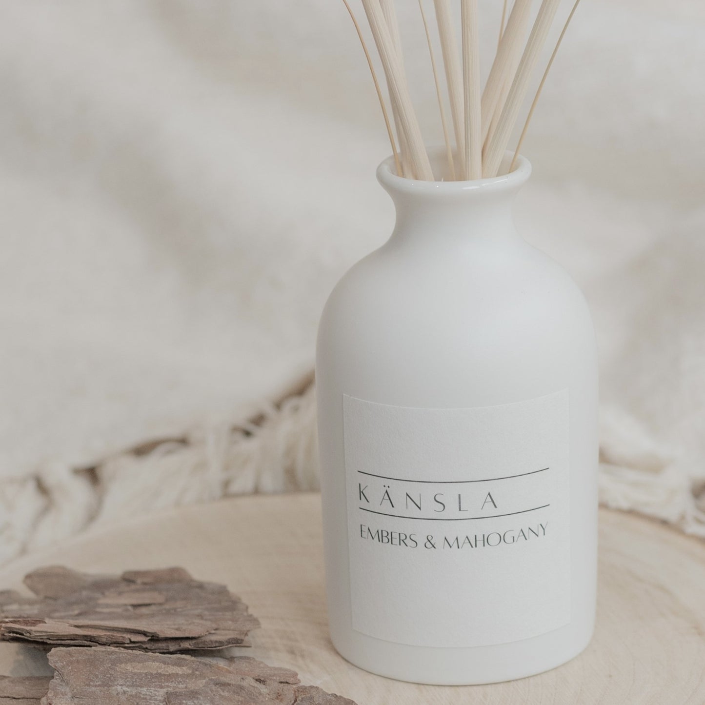 White ceramic reed diffuser with natural reeds in embers and mahogany scent