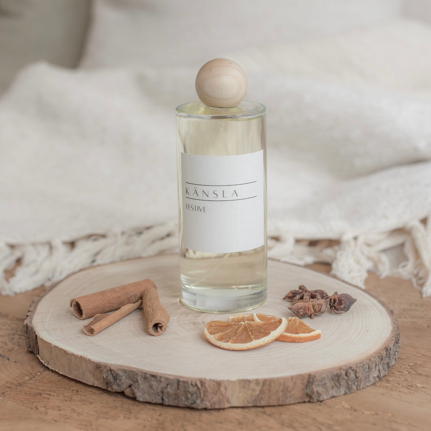 Room spray bottle in a festive scent with wooden lis and festive decorations on a wooden tray