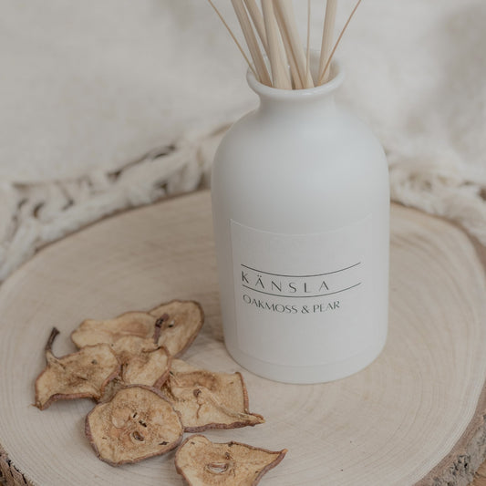 Close up image of a White ceramic reed diffuser with natural reeds and dried bunny tails oakmoss and pear scent