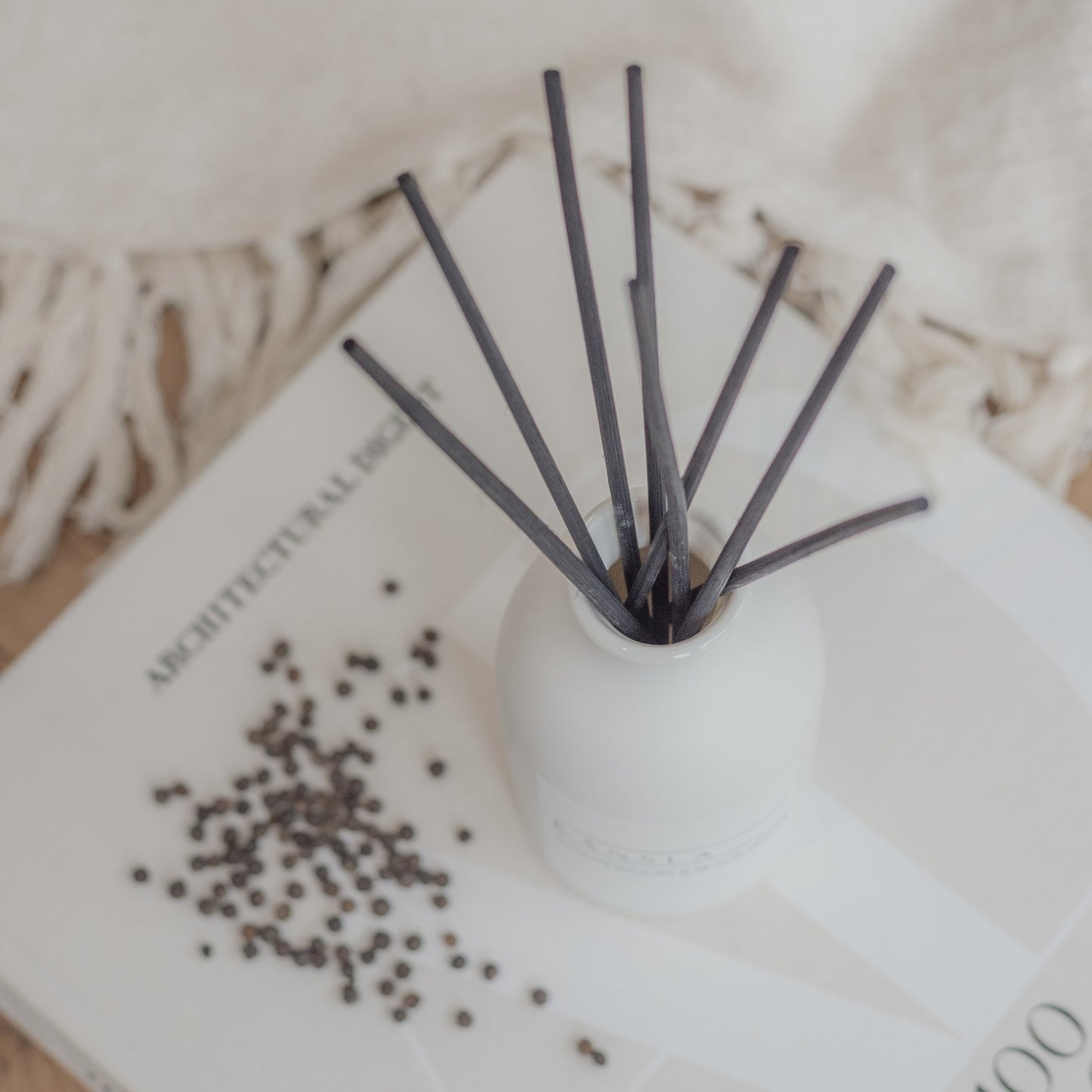 Close up of black rattan reeds in white ceramic reed diffuser sandalwood and black pepper