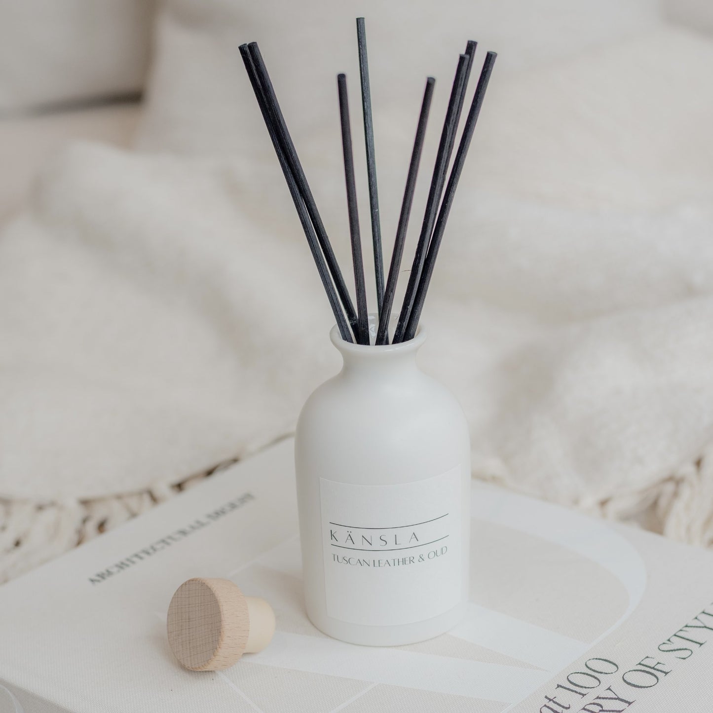 White reed diffuser with black rattan reeds and white label kansla tuscan leather and oud