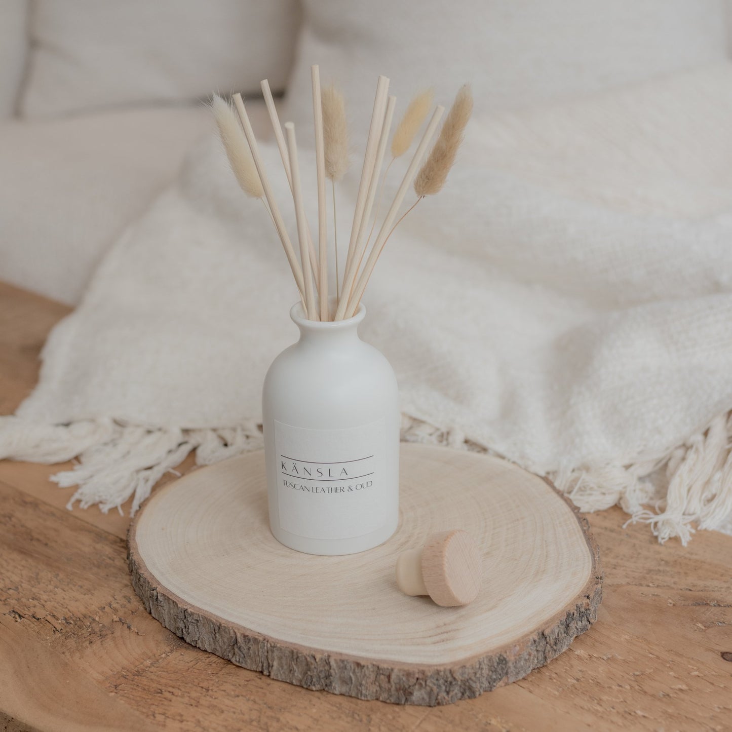 white ceramic reed diffuser with natural rattan reeds and decorative dried bunny tails tuscan leather and oud