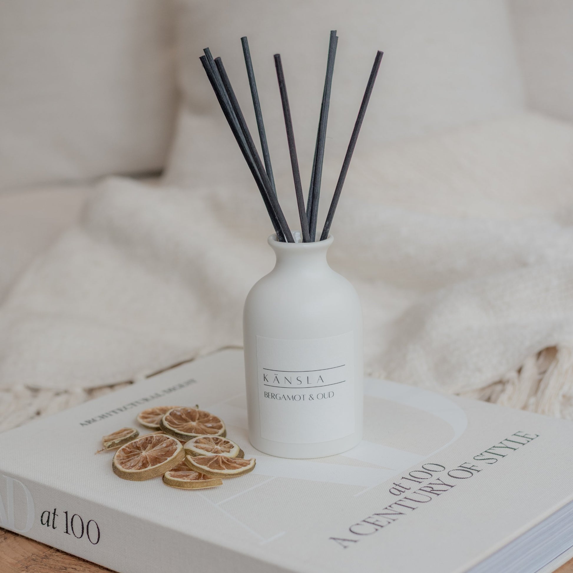 White ceramic reed diffuser on a book with black rattan reeds