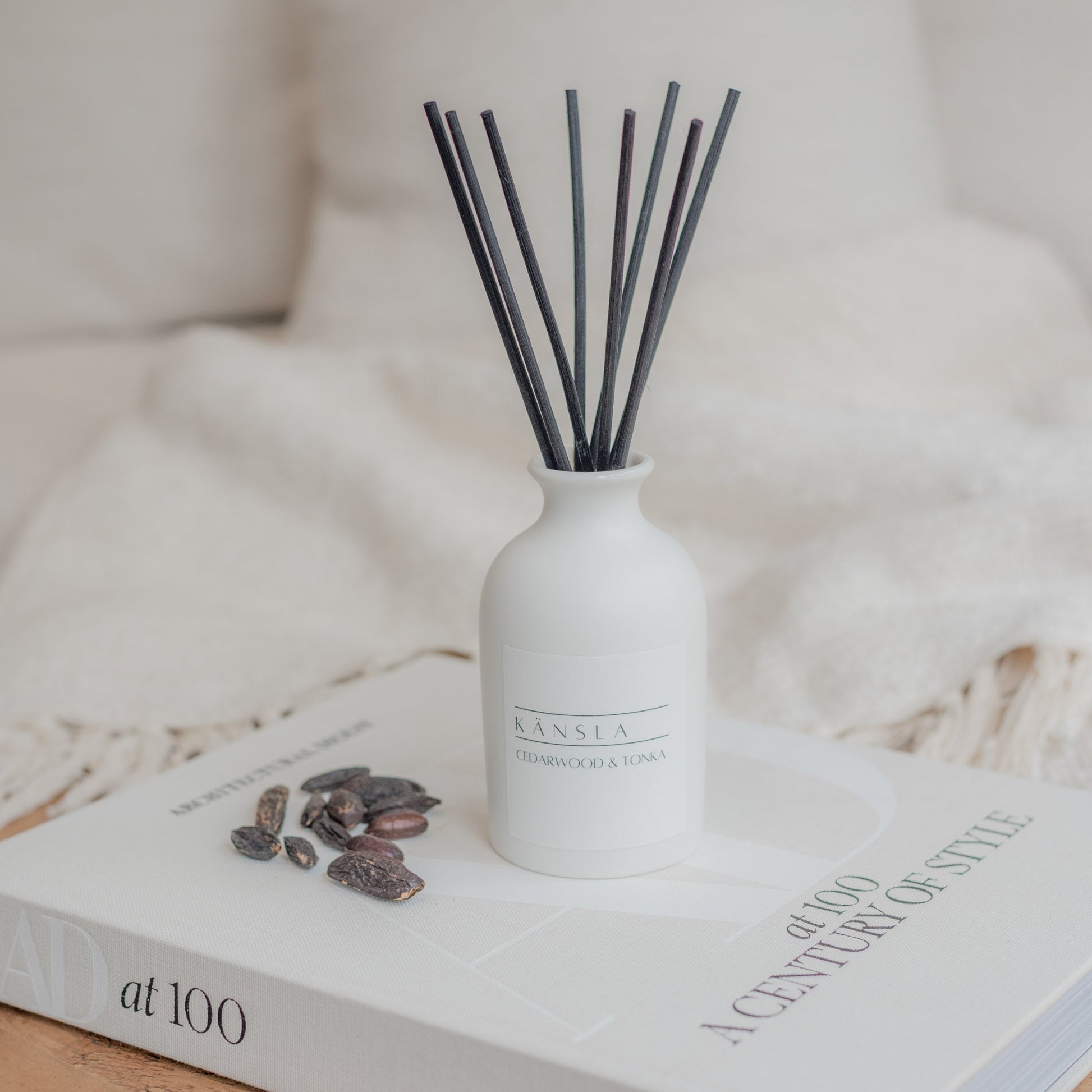 Cedarwood and tonka reed diffuser in white ceramic bottle with white label and black rattan reeds