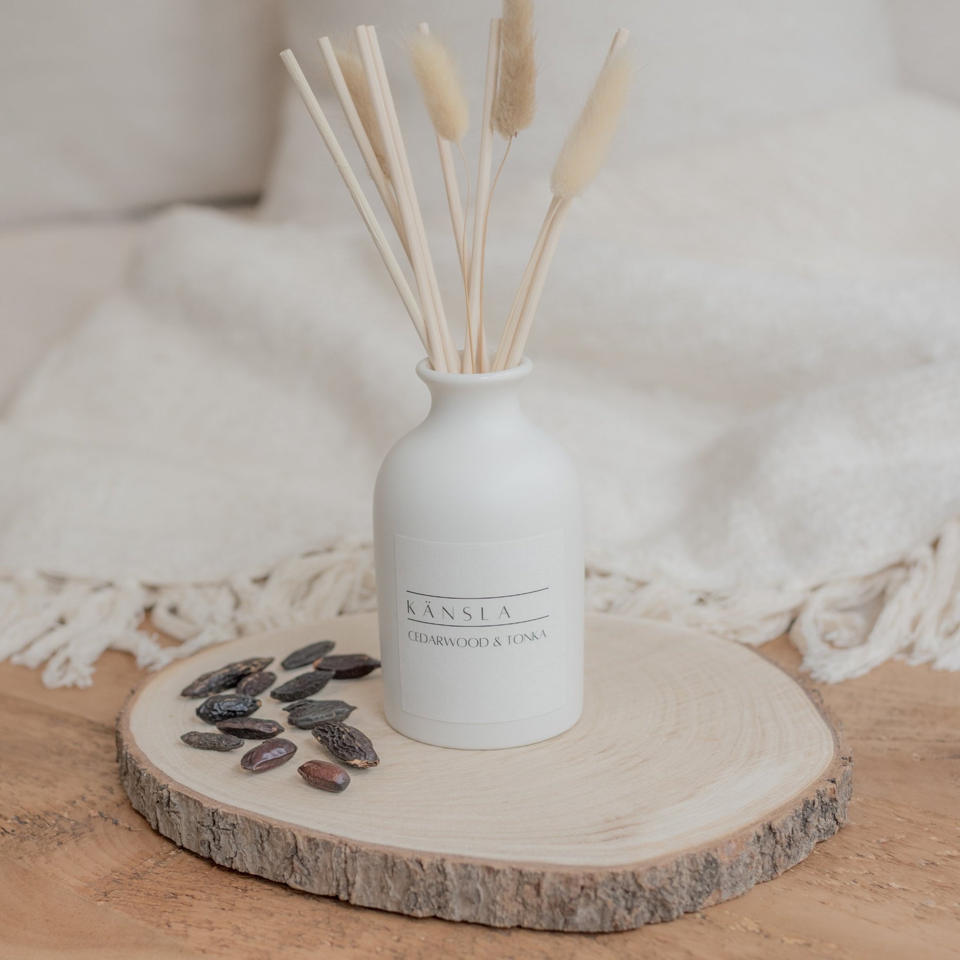 White ceramic reed diffuser with natural rattan reeds and decorative dried bunny tails cedarwood and tonka scent