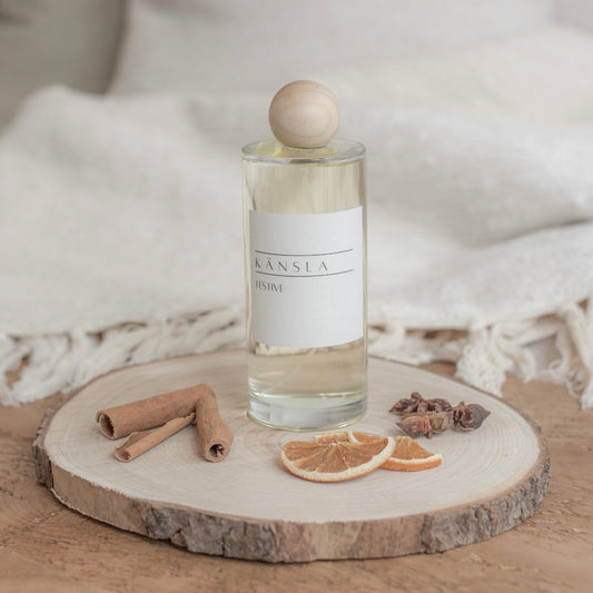 Room spray bottle in a festive scent with wooden lis and festive decorations on a wooden tray