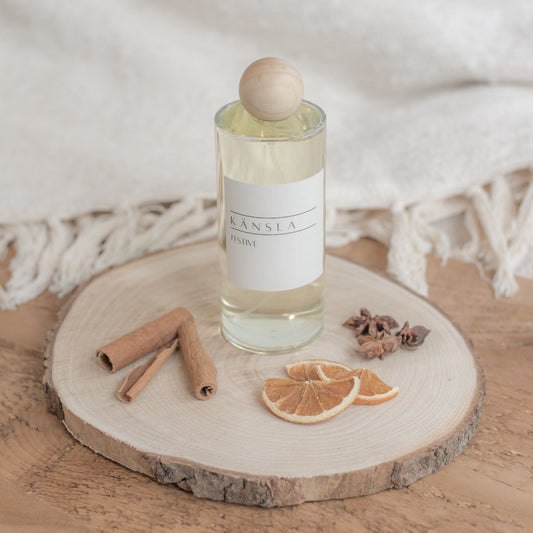 Festive scented room spray with a Kansla white label on the front a wooden lid in a clear glass bottle