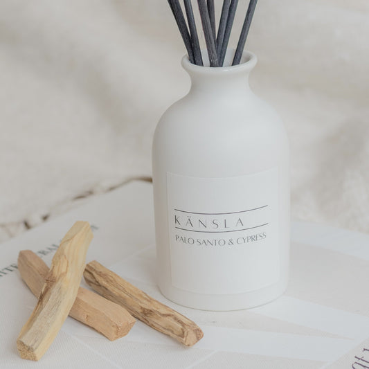 Close up of White ceramic reed diffuser with black reeds palo santo and cypress