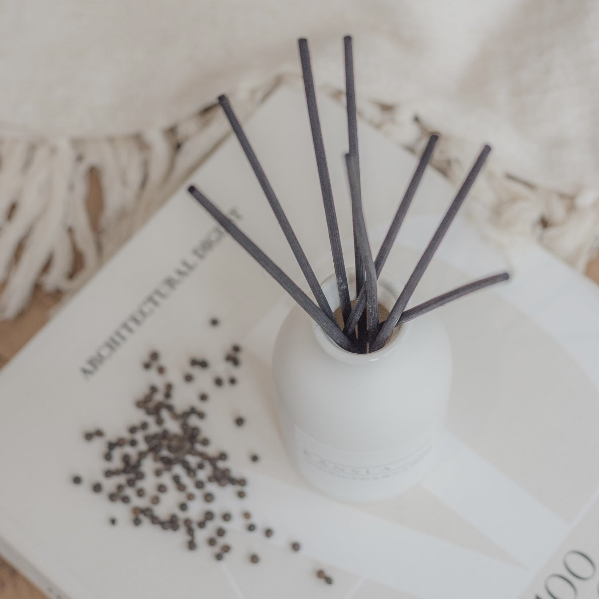 Close up of black rattan reeds in white ceramic reed diffuser sandalwood and black pepper
