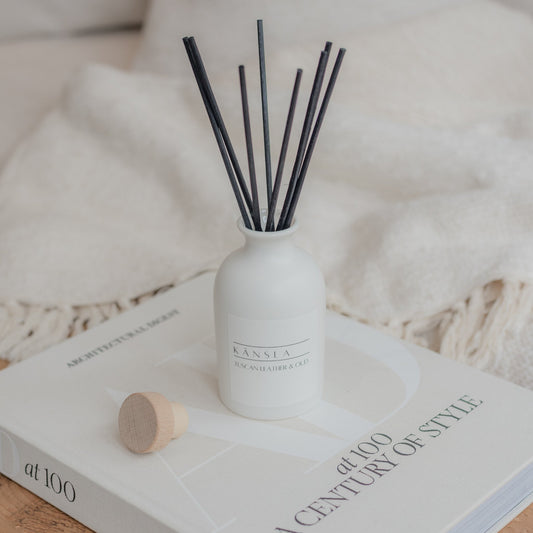 white reed diffuser bottle with black rattan reeds tuscan leather and oud